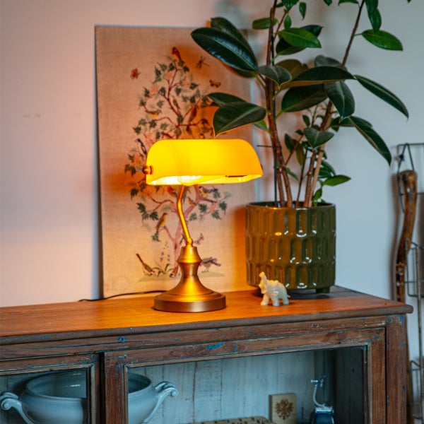 Dekorative Szene mit einer gelben Bankerlampe, Zimmerpflanze und einem Schrank