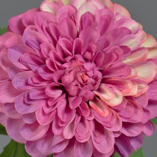 Detailaufnahme künstlicher grüner Blätter an einem Stängel, ein Teil einer Blüte ist sichtbar.