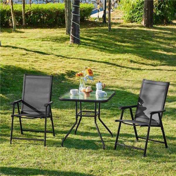Gartenmoebel-Set bestehend aus zwei klappbaren Gartenstuehlen mit Textilgewebe und einem quadratischen Glastisch im Freien auf einem Rasen.