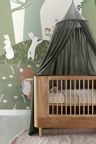Babyzimmer mit Kinderbett, Baldachin und Waldtapete