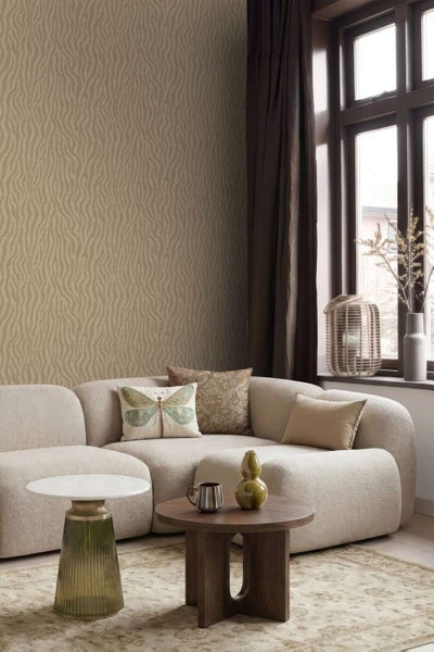 Wohnzimmer mit moderner Vliestapete mit wellenförmigem Textilmuster, kombiniert mit einem hellen Sofa und einem Holztisch vor dem Fenster.