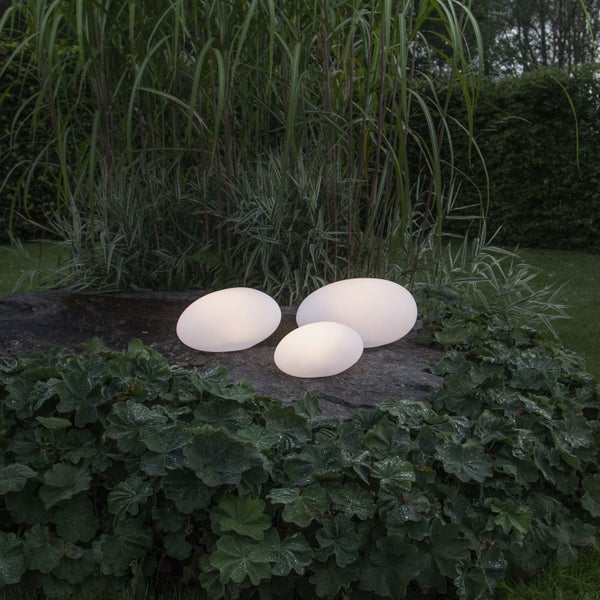Drei leuchtende Gartenleuchten in Ei Form auf einem Stein mit Pflanzen