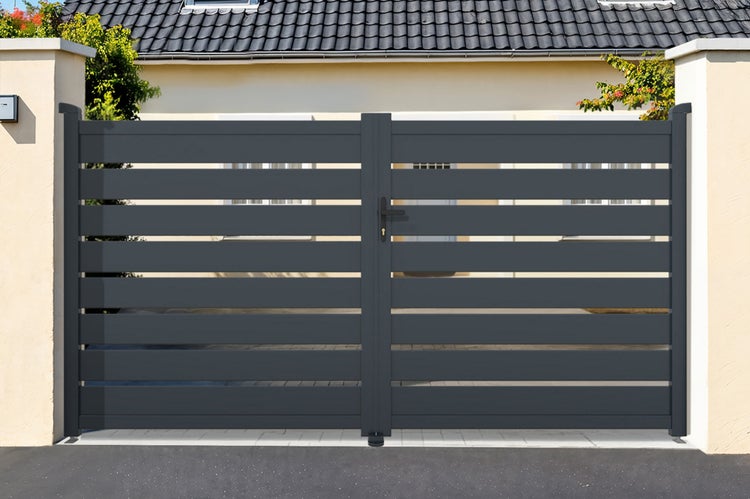 Zweiflügeliges Einfahrtstor mit horizontalen Lamellen aus Aluminium, montiert zwischen zwei Mauerpfeilern vor einem Wohnhaus.