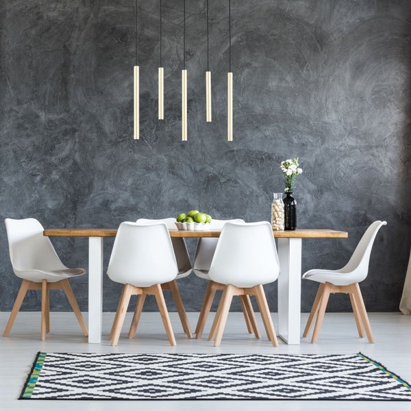 Modernes Esszimmer mit Holztisch und vier Stühlen vor strukturierter Wand mit Pendelleuchten und grafischem Teppich.