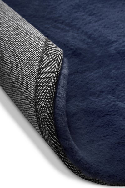 Detailaufnahme eines dunkelblauen, flauschigen Kunstfell-Teppichs mit gewebter Rückseite.
