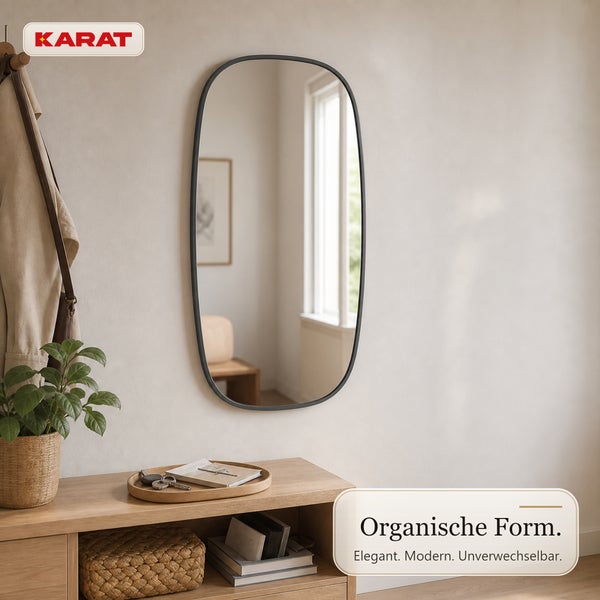 Karat Logo und Wandspiegel mit ovaler Form und Rahmen in modernem Flurbereich mit Holzkommode und Pflanze.