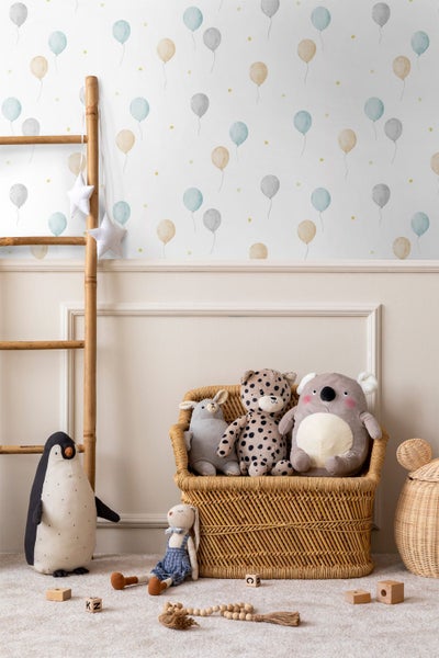Kinderzimmertapete mit Luftballon- und Sternenmuster in einem hellen Zimmer mit Bambusleiter und Stofftieren in einem Weidenkorb.