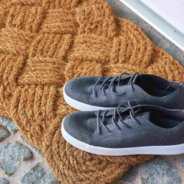 Fußmatte aus Kokosfaser mit geflochtenem Muster und Paar Schuhe