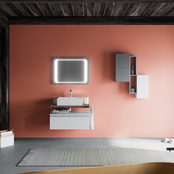 Modernes Badezimmer mit korallenroter Wand, weißem Waschtisch mit LED-Spiegel und grauen Hängeschränken vor Holzbalkendecke.