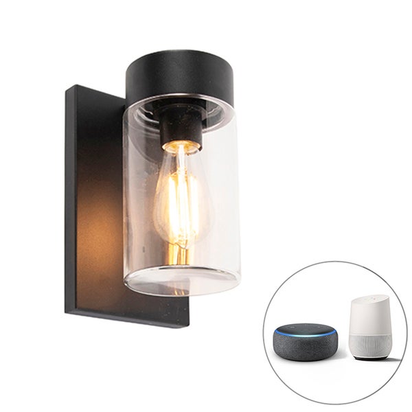 Schwarze Außenwandleuchte mit Glaszylinder, leuchtendem Filament-Leuchtmittel und Symbolen für Smart-Home-Steuerung.