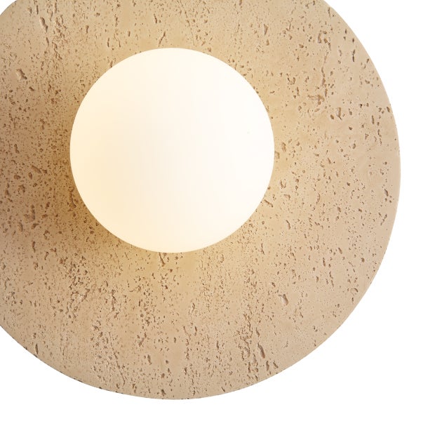 Wandleuchte mit runder Basis in Betonoptik und einem kugelförmigen Leuchtschirm aus Glas.
