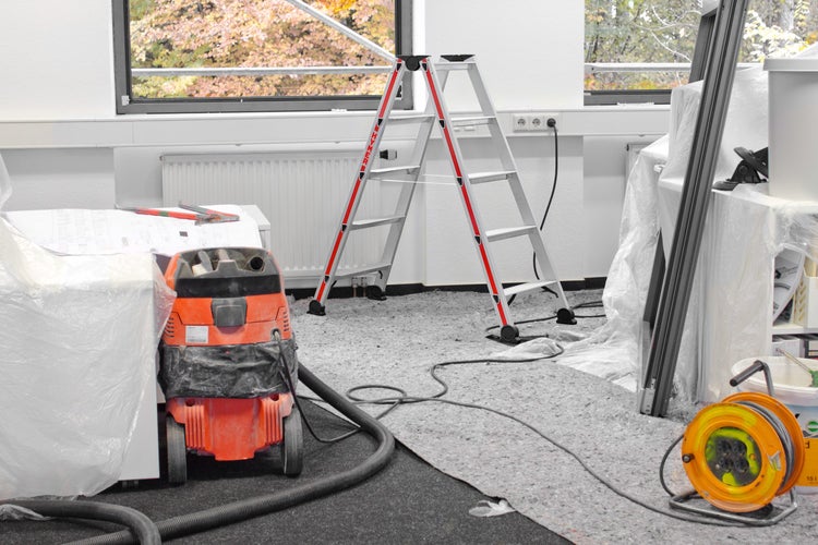 Innenaufnahme eines Zimmers mit einer Leiter, einem Staubsauger und verschiedenen Werkzeugen