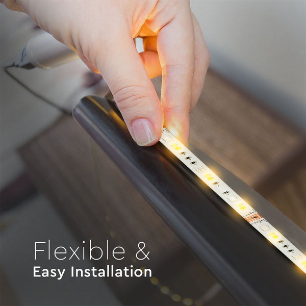 Eine Hand klebt einen leuchtenden, flexiblen LED-Streifen auf eine dunkle Oberfläche.