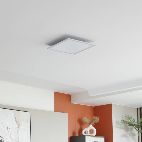 Quadratisches LED-Panel an einer weißen Decke in einem modern eingerichteten Raum.