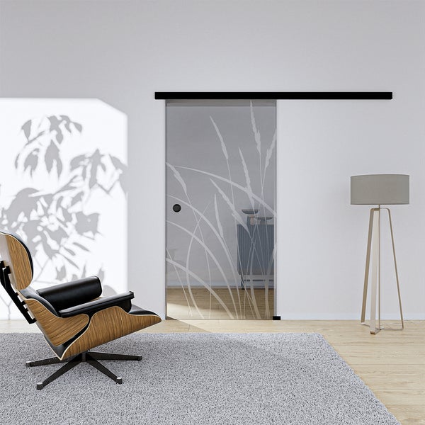 Ganzglas-Schiebetür mit Gräser-Motiv und schwarzer Laufschiene in einem modernen, hellen Wohnraum.