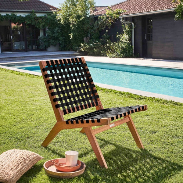 Gartenstuhl aus Holz mit schwarzer Bespannung auf einer Rasenfläche neben einem Pool.