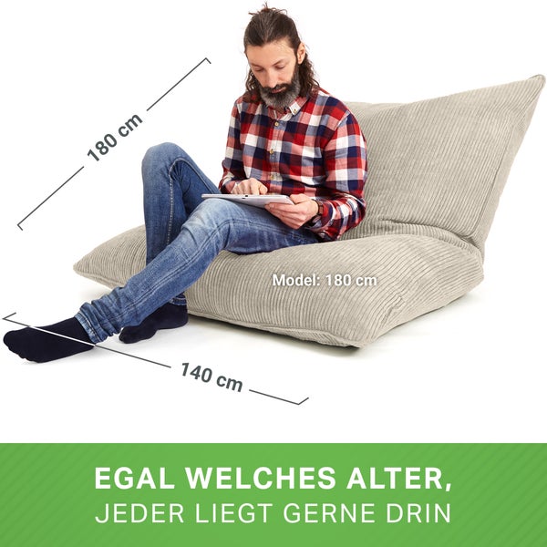 Mann sitzt auf einem grauen Cord-Sitzsack mit den Maßen 180 cm mal 140 cm und nutzt ein Tablet.