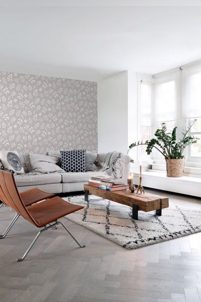 Wohnzimmer mit Sofa, Couchtisch aus Holz, Teppich und gemusterter Tapete