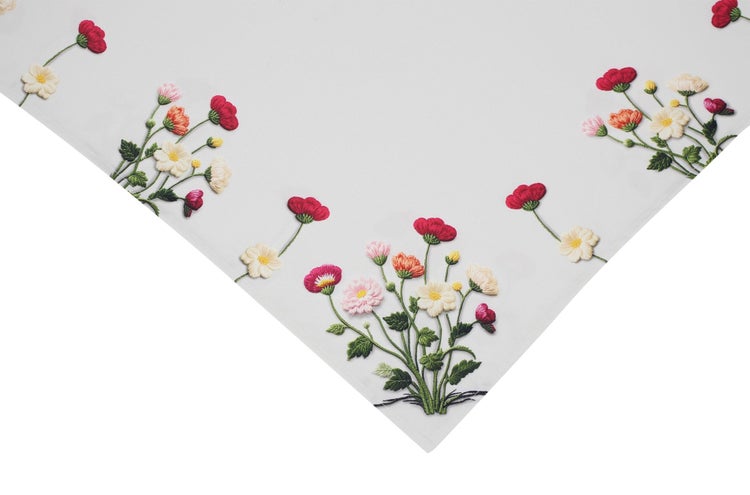 Textil mit bunter Blumenstickerei, die verschiedene Blüten und grüne Blätter zeigt.