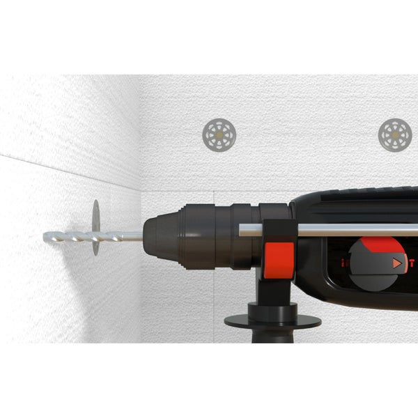 Eine Bohrmaschine bohrt ein Loch in eine Wand mit Dämmstoffdübeln.