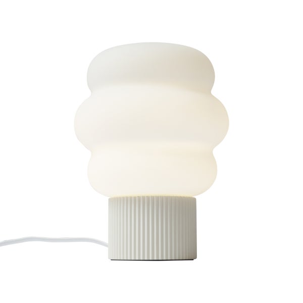 Moderne weiße Tischleuchte mit wellenförmigem, lichtdurchlässigem Schirm und zylindrischem, geriffeltem Sockel.