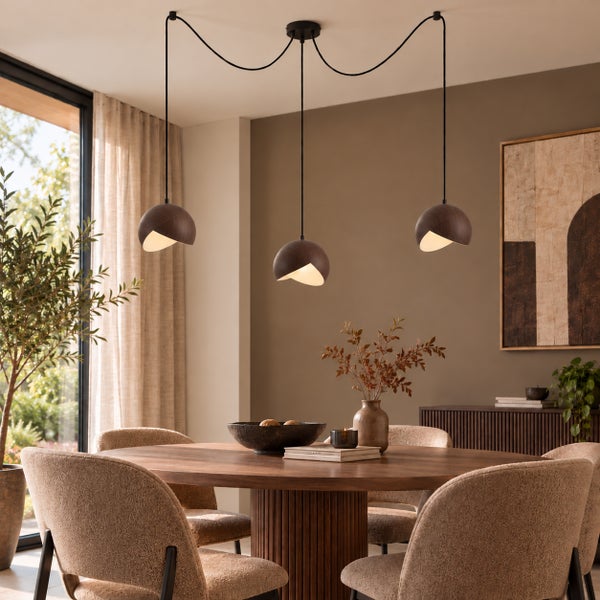 Moderne Esstischlampe mit drei hängenden Leuchten über einem runden Holztisch in einem gemütlichen, stilvoll eingerichteten Esszimmer.