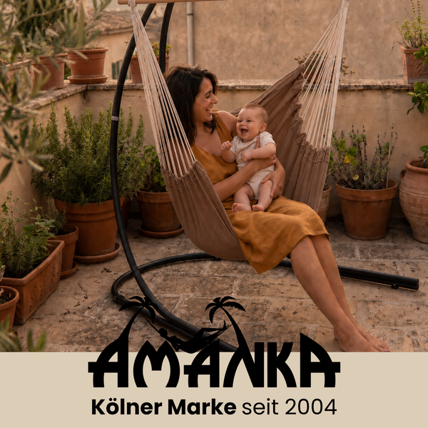 Mutter mit Baby in einem freistehenden Hängesessel auf einer Terrasse zwischen vielen Pflanzentöpfen. Amanka Logo.