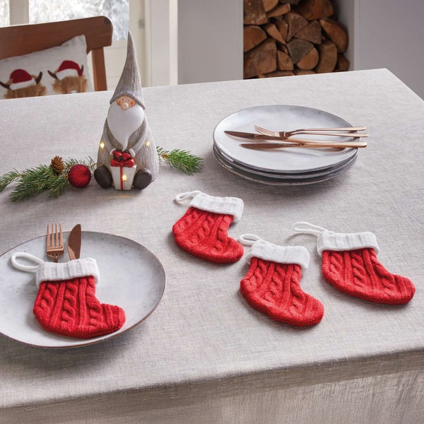 Festlicher Tisch mit Dekorationswichtel, Geschirr, Besteck und gestrickten Strumpf-Bestecktaschen.