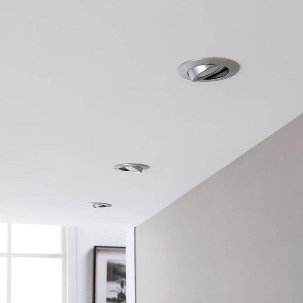 Drei schwenkbare Einbaustrahler aus Metall, in einer Reihe in einer weißen Decke in einem hellen, modernen Raum installiert.