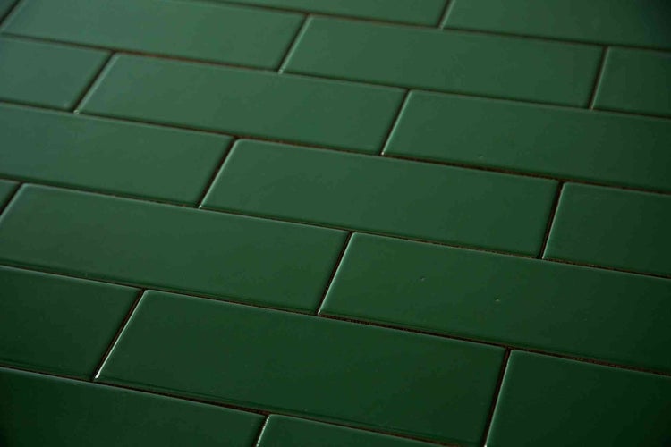 Grüne glänzende Wandfliesen im Metro-Stil, rechteckig, im Versatz verlegt.
