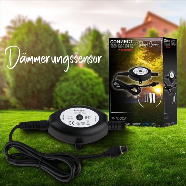 Schwarzer Dämmerungssensor von Briloner für den Außenbereich mit Schutzklasse IP67 auf einer Rasenfläche, inklusive Produktverpackung.