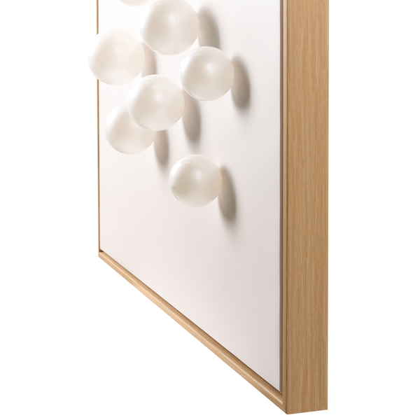 Wanddekoration mit dreidimensionalen weißen Kugeln auf Leinwand in einem Rahmen in Holzoptik.