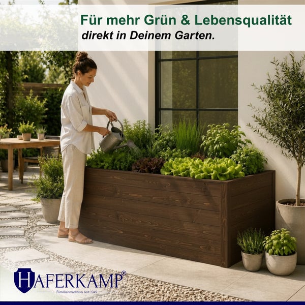 Eine Frau gießt Salat und Kräuter in einem großen, dunkelbraunen Holz-Hochbeet auf einer Terrasse. Haferkamp Logo.