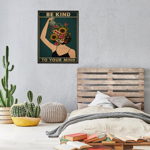 Ein Kunstdruck mit dem Motiv Be Kind To Your Mind in einem Schlafzimmer mit Palettenbett, Kakteen und auf dem Boden verteilten Büchern.