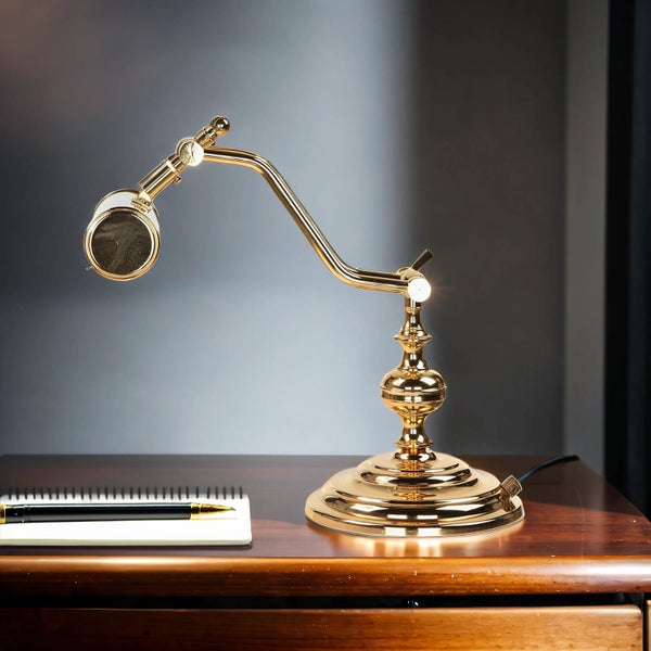 Goldene Schreibtischlampe mit Notizblock und Stift auf einem Tisch