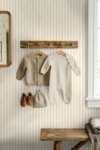 Vliestapete mit vertikalen Streifen und floralen Rankenmustern in einem Kinderzimmer mit Holzgarderobe und Babykleidung.