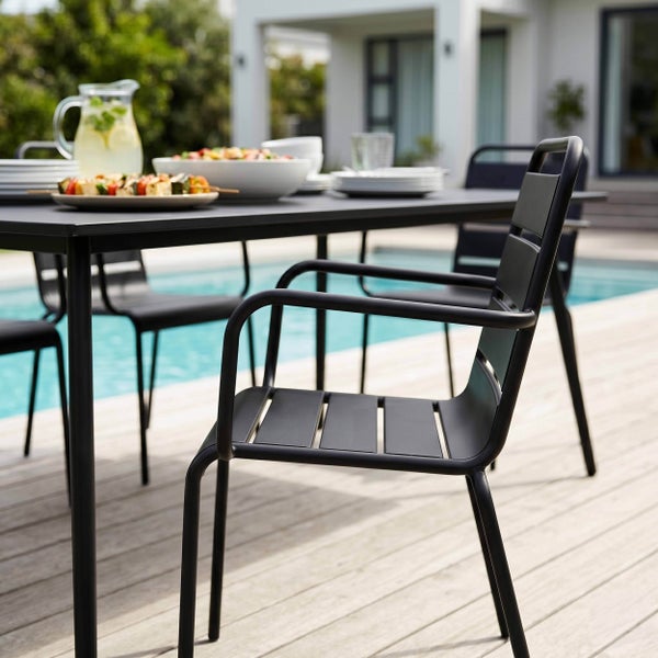 Schwarzes Gartenmöbel-Set aus Metall mit rechteckigem Tisch und Stühlen mit Armlehnen auf einer hellen Holzterrasse am Pool.
