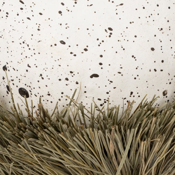 Dekorative Grasbüschel vor einem dekorierten Gefäß.