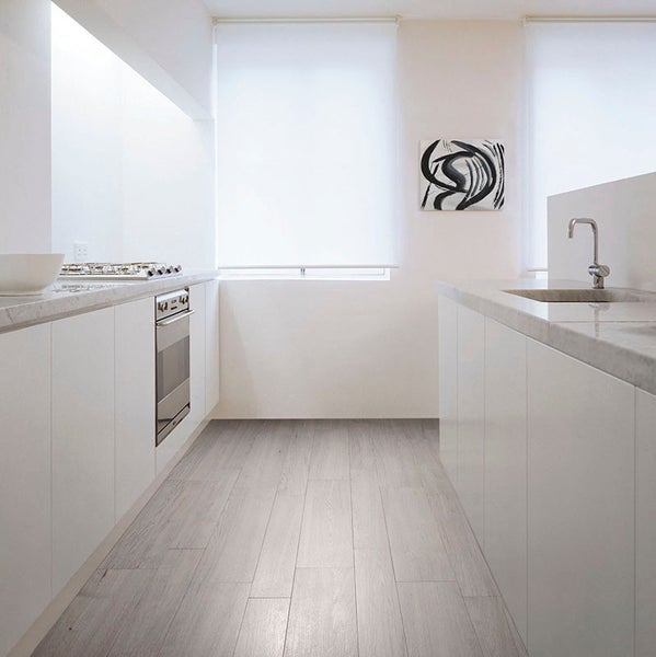 Moderne, minimalistische Einbauküche mit hellen Holzoptik Bodenfliesen, weißen Küchenfronten, Marmorarbeitsplatte und integrierten Küchengeräten.