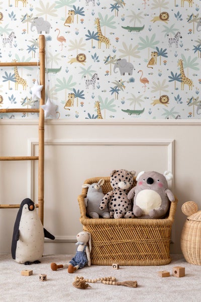 Helles Kinderzimmer mit Safari-Tapete, Bambusleiter und Stofftieren in einem Korbsessel vor einer Wand mit Zierleisten.