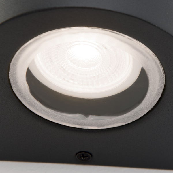 Detail einer eingeschalteten runden LED-Außenleuchte mit schwarzem Gehäuse.