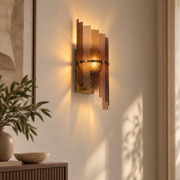 Moderne Wandleuchte mit strukturierten Glaslamellen in warmem Lichtschein an einer Wohnzimmerwand