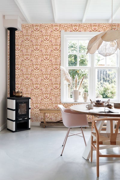 Heller Raum mit floral gemusterter Tapete, Esstischgruppe und Kaminofen