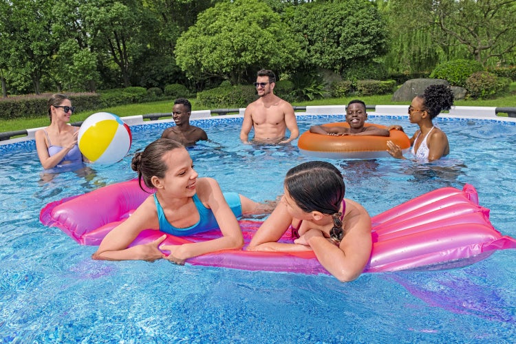 Personen im runden Aufstellpool mit aufblasbarer Luftmatratze, Schwimmring und Wasserball in einem hellen Garten.