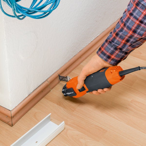 Oszillierendes Elektrowerkzeug beim Kürzen einer Holzfußleiste