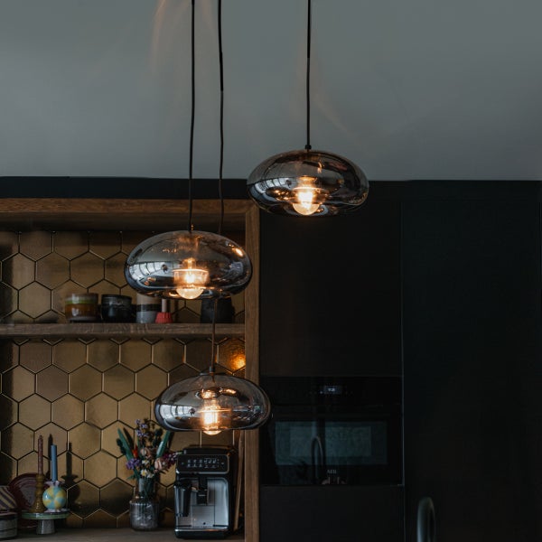 Drei Pendelleuchten mit runden Schirmen in einer Küche.