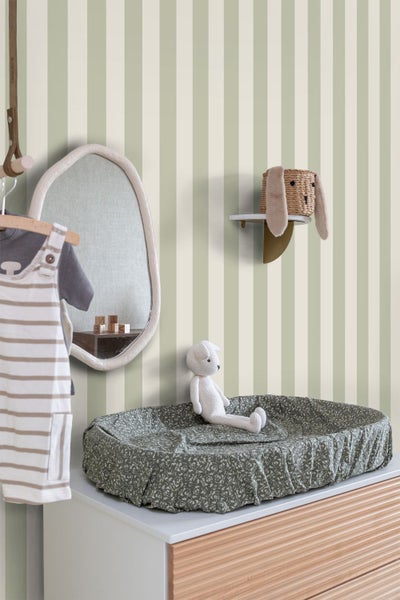 Vliestapete mit vertikalen Streifen in einem hellen Kinderzimmer mit Wickelkommode, organisch geformtem Spiegel und Wandregal.