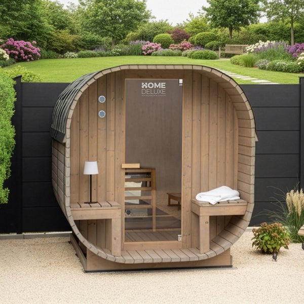 Fasssauna aus Holz für den Garten mit Glastür und zwei Außenbänken sowie Home Deluxe Logo im Außenbereich vor einem Zaun.