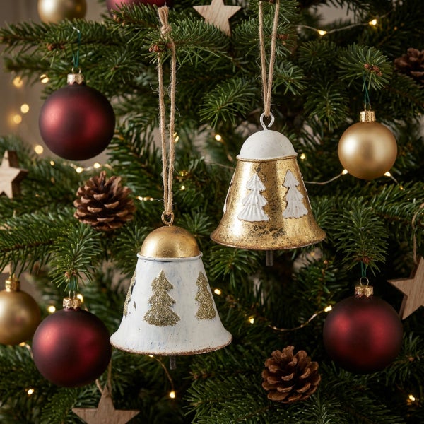 Zwei dekorative Weihnachtsglocken aus Metall als Baumschmuck, hängend an einem Weihnachtsbaum mit Kugeln und Tannenzapfen.