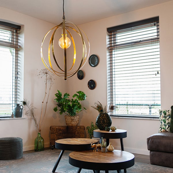Wohnzimmer mit runden Couchtischen und goldfarbener Kugel-Hängeleuchte
